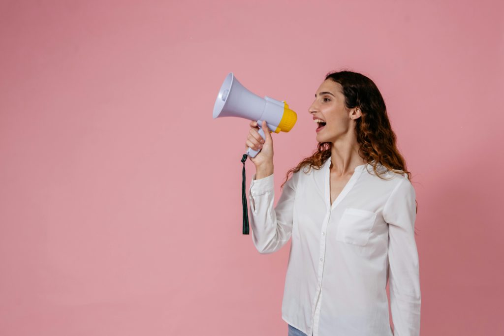 How to pitch brands professionally as a small creator. Women shouting into a megaphone.