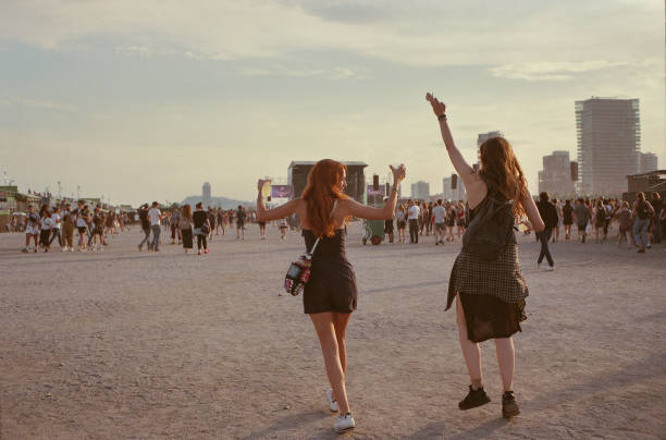 Two girls at a festival throwing their hands up in the air.