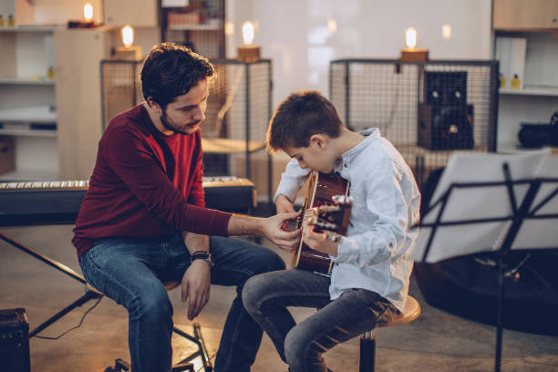 Man teaching boy how to play the guitar