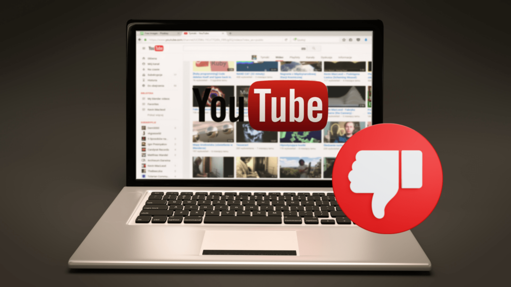 Black background with a laptop in the foreground. On the laptop, YouTube is loaded up, the logo sits at the front of the laptop. There is a thumbs down emoji in a red circle on the right side of the laptop.