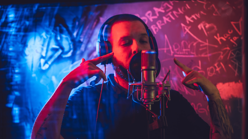 Musician singing into a microphone, wearing headphones against a urban background.