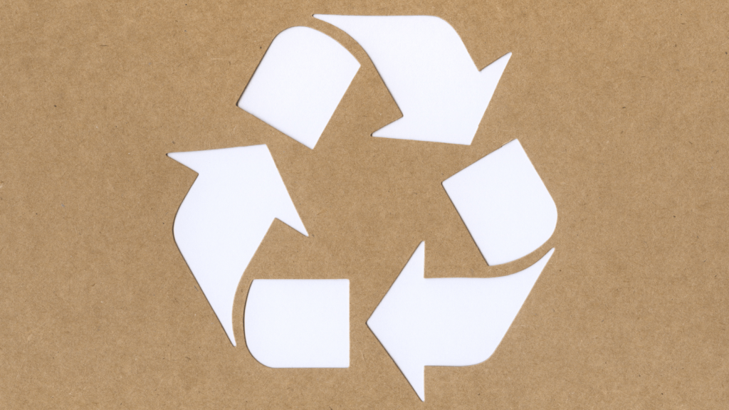 Brown kraft style background. In the foreground is a white recycle triangle. 