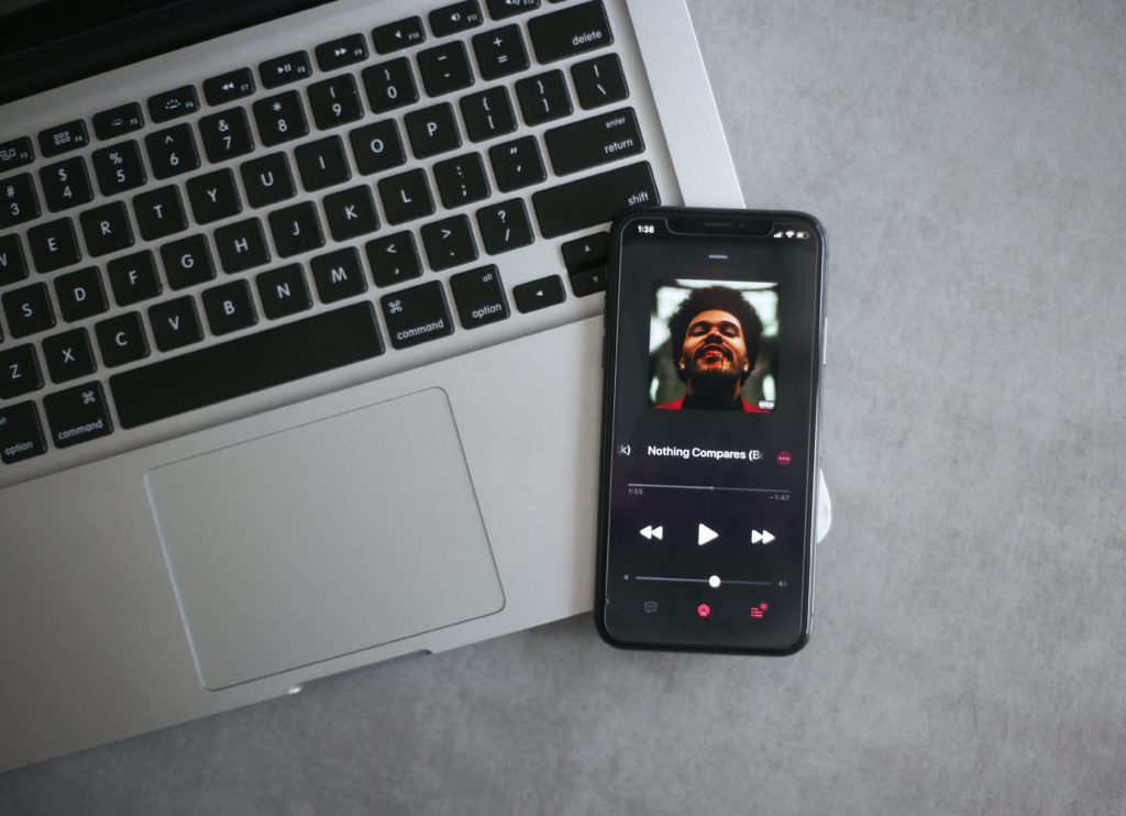 Listening Now - Apple Music's real-time analytics. Photo of a Macbook with an iPhone on the keyboard.