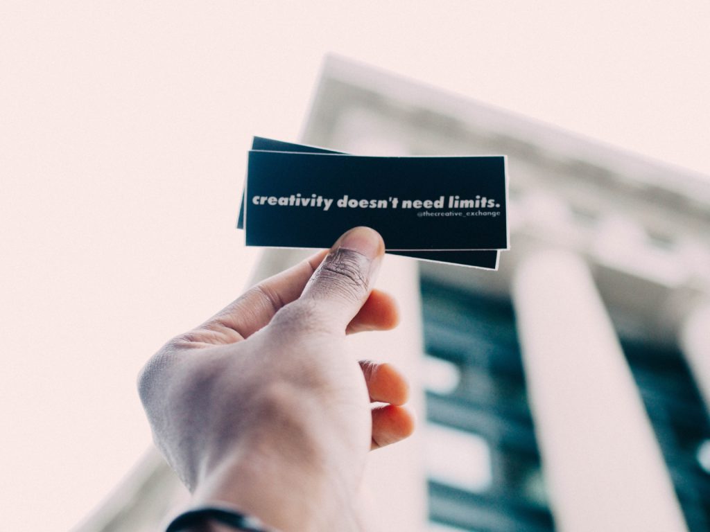 5 careers in a creative industry. Photo of someone holding a piece of paper saying 'creativity doesn't need limits.'