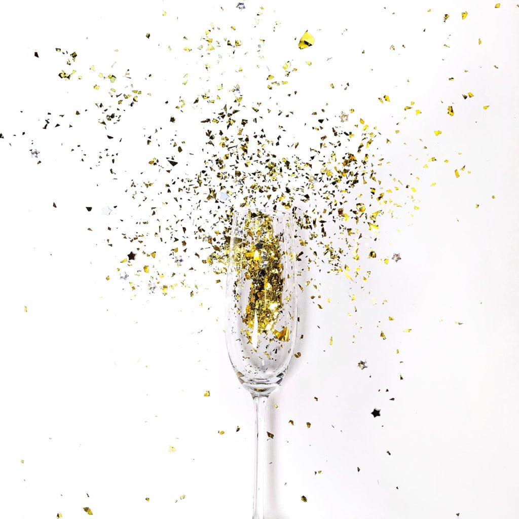 Ideas for content creators to ring in the New Year. Photo of a prosecco glass with glitter coming out of it.