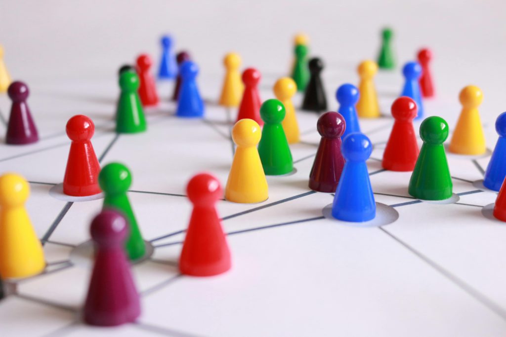 The important of networking for artists - connections you can't ignore. Photo of lots of coloured games counters. All placed in their own circle on a connecting pattern.