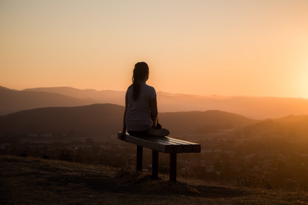 5 important tips for a healthier mindset and digital lifestyle. Photo of a girl sat on a bench looking out to the mountains. 