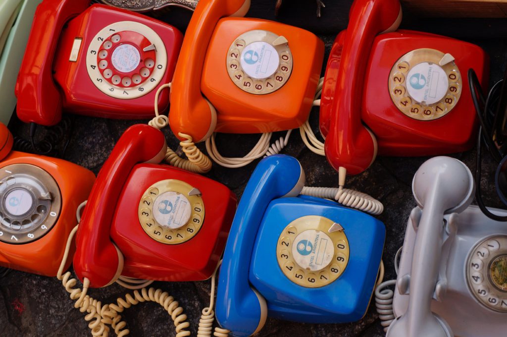 Small businesses - should you be giving out your phone number? Photo of multiple dial up corded retro phones in different colours.