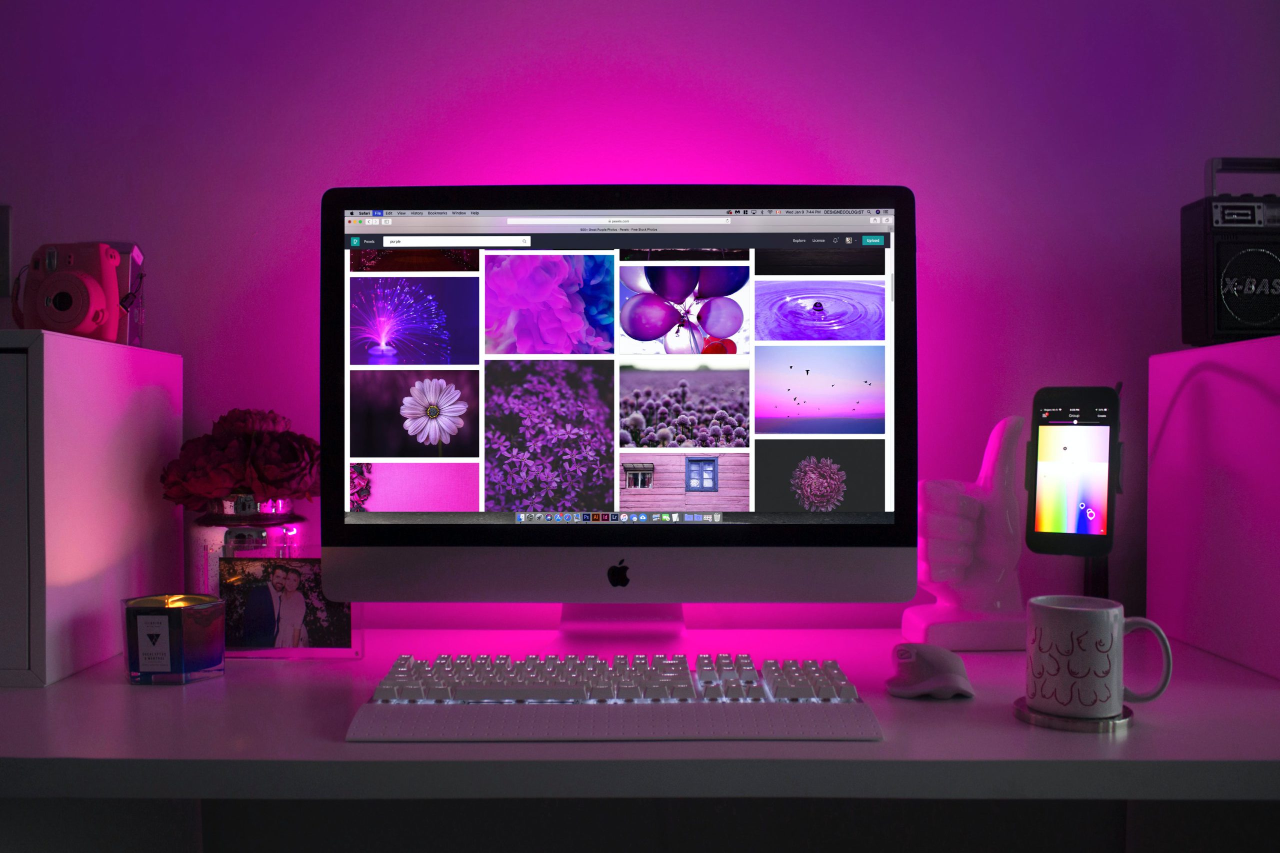 The benefits of Pexels for content creators - easy access images. Purpple lit room. Displaying a desk with a Apple Mac on, as well as other items. Pexels is displayed on the computer.