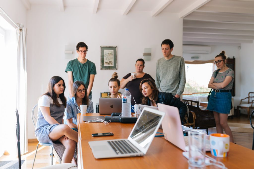 A beginner's guide to finding a creative internship. Photo of multiple people gathered around a laptop within an office.