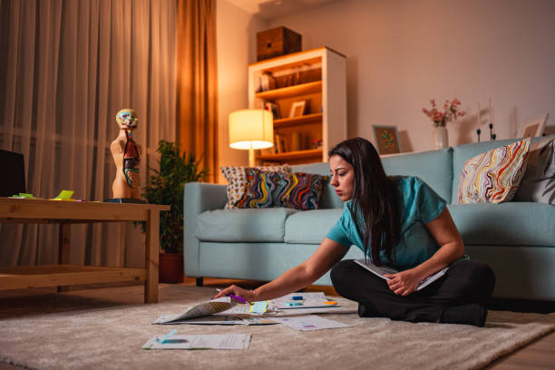 Explaining the ins and outs of medical illustrators. Photo of a girl sat on the floor of a living room surrounded by textbooks and paper. On the side is a model of the human body.
