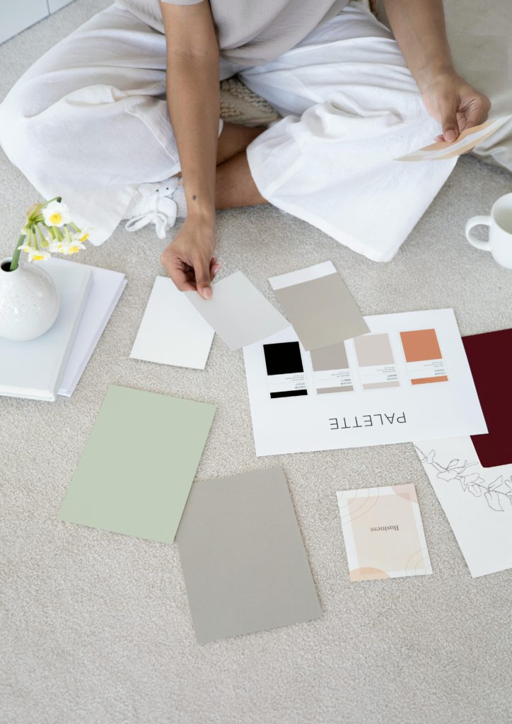 Crafting your identity - how to build a strong personal brand as an independent artist. Photo of a woman placing multiple colour swatches on the floor, with her Palette printed out.