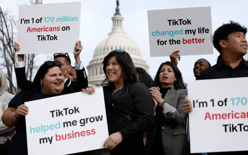 America's TikTok ban - updates of 2024. Photo of lots of people with signs at a protest. All saying positive things about TikTok.
