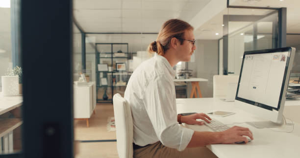 Essential free resources every content creator should use. Photo of a man sat at a desk from a side view. He is working on an Apple iMac.