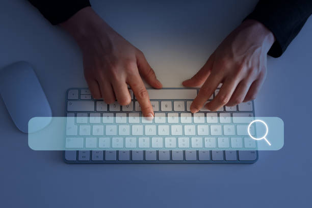 Navigating the challenges of Instagram's explore page. Photo of a Mac keyboard with someone's hands on it ready to type. Next to the keyboard is a Mac wireless mouse. On the keyboard is a big search bar.