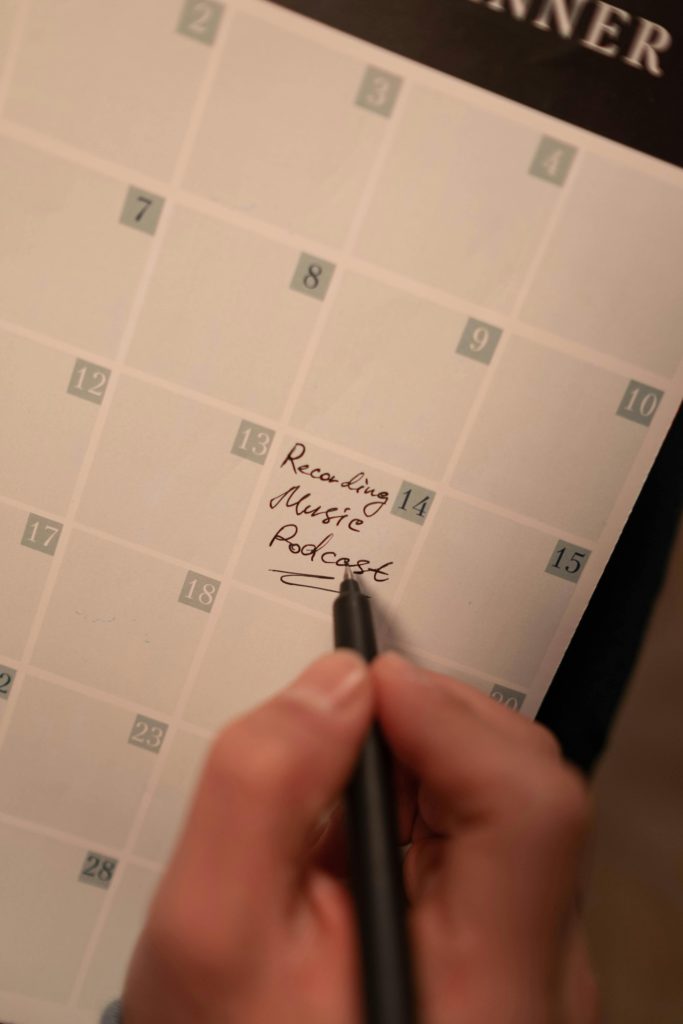 How to create a simple content calendar - a step-by-step guide. Photo of someone writing onto a calendar "recording music podcast"