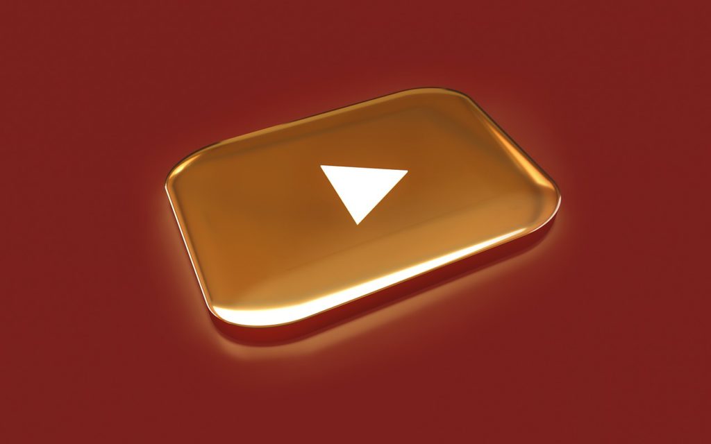YouTube Music will restart from where you left it on the web app. Dark red background, with gold YouTube play button.