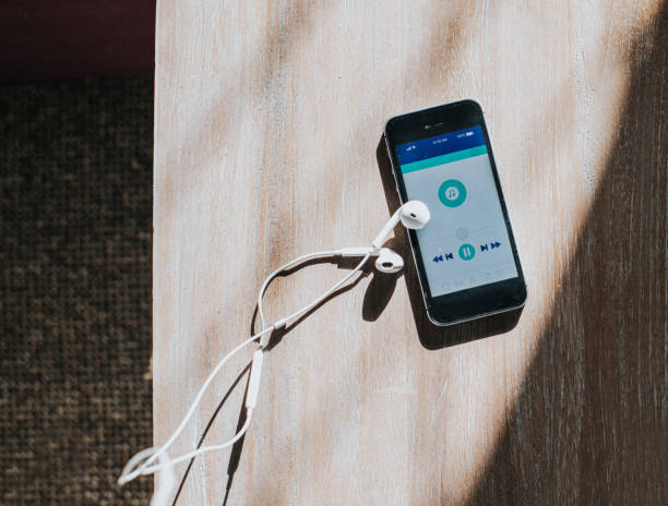 The role of playlists in music discovery - getting your music featured. Photo of a smartphone with Spotify displayed. On the table with the phone are a pair of earphones.