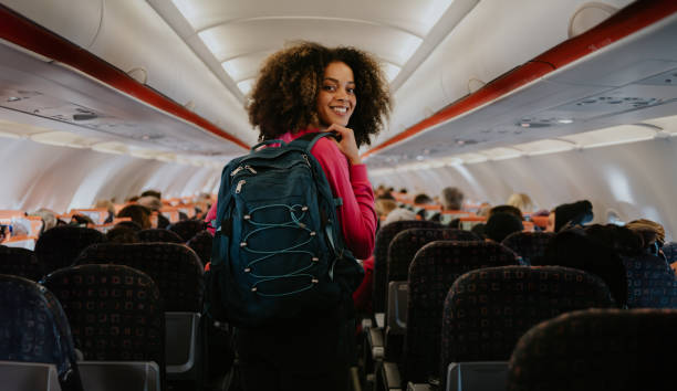 How to become a travel blogger - a step-by-step guide. Woman with her backpack on walking down plane isle.