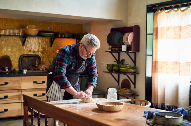 Can hobbies take over your life too much? Man rolling dough on a table in a kitchen.