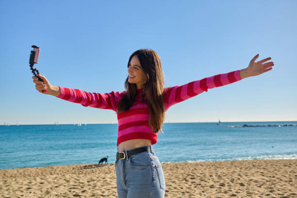 How to find your content creating style. Girl on a beach talking to a camera with arms in the air.