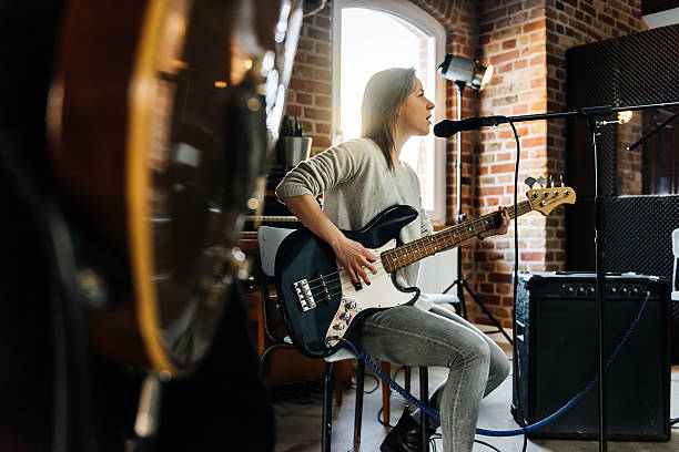 Understanding independent musicians - who they are and how they thrive. Photo of a person sat on a chair with an electric guitar singing into a microphone.