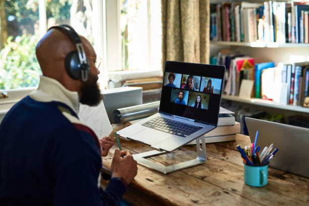 Setting up your workspace and staying focused. Man sat on Zoom call at his desk at home.