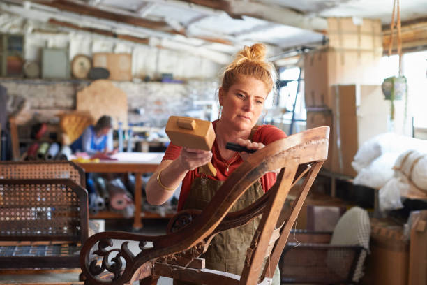 How to get started as a business with minimal resources. Woman hammering a chair, creating a piece of furniture.