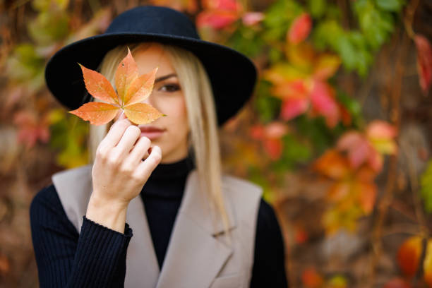 1. Autumn aesthetic photoshoots. Woman holding leaf up to face.