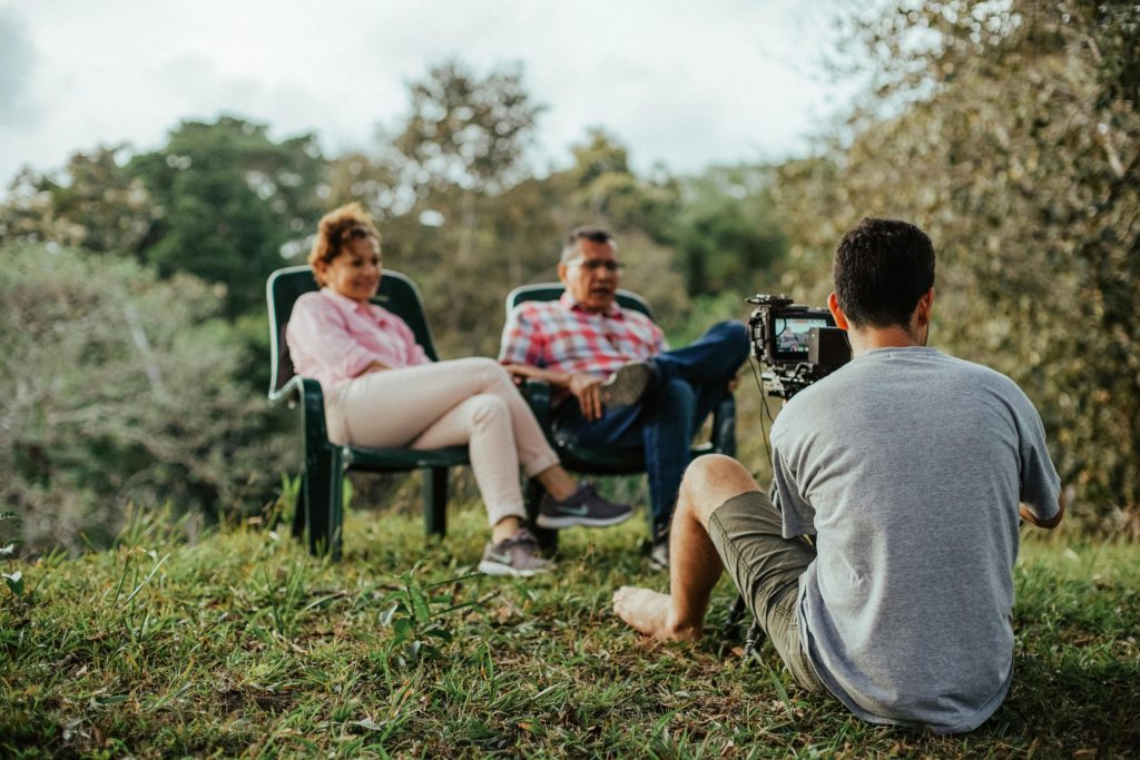 Top 10 careers you can pursue in the media industry. Photo of a man from the back recording two people sat in chairs.