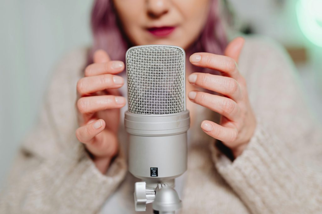 What is an ASMR artist? Photo of a woman up close tapping on a microphone.