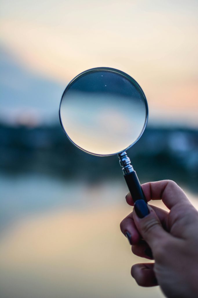 Why it’s hard to get noticed - limited discovery for niche content on Twitter. Photo of a magnifying glass being held against a blurred background.