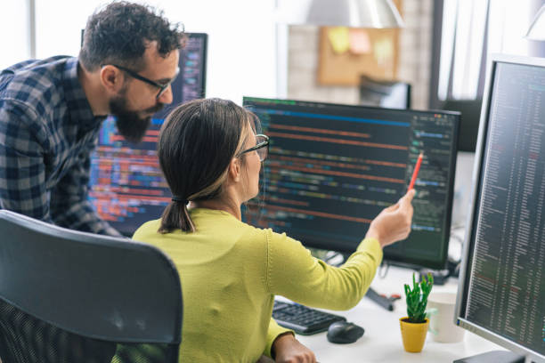 Can I use AI to edit my videos? Photo of two people looking at a computer at code.