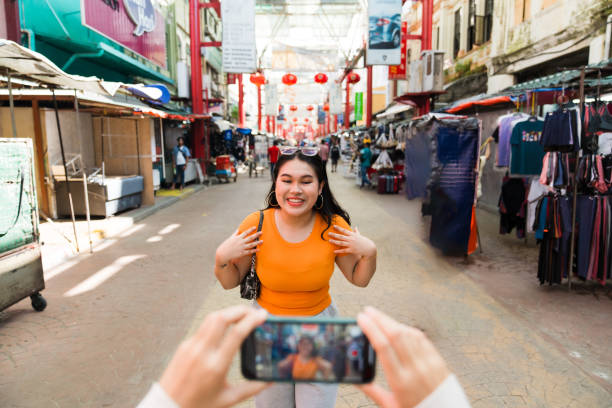 How to shoot high-quality outfit reels with a phone. Photo of a girl stood in a market being recorded on a smartphone.