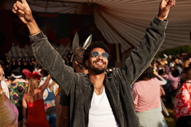 How to get booked for music festivals. Photo of a man with his arms in the air at a festival.