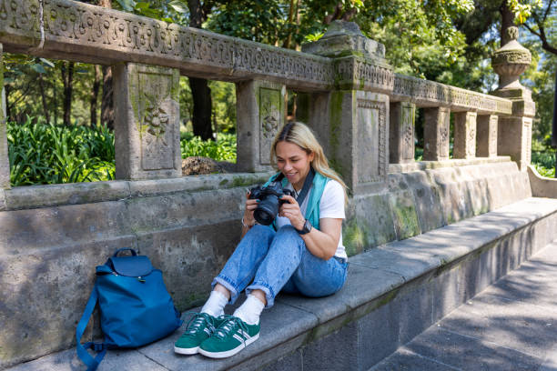 How do I shoot in manual mode? Photo of a girl sat outside looking at her camera and smiling.