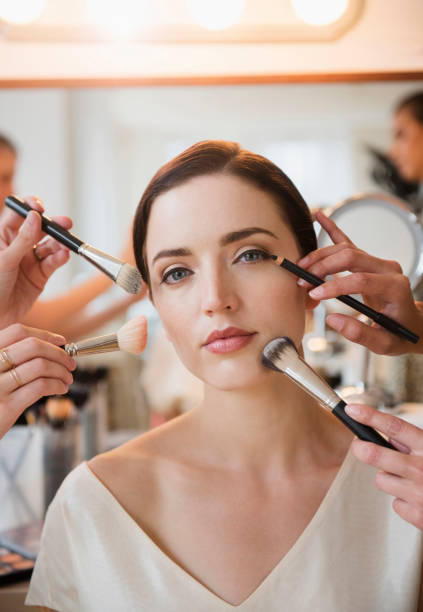 How do I build a makeup artist portfolio? Photo of a woman having makeup put on by multiple brushes at once.