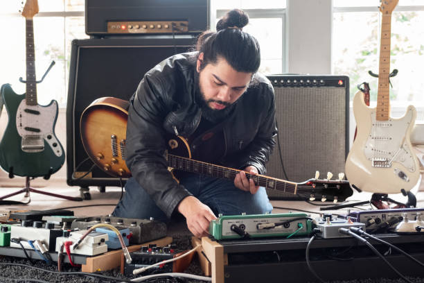 Layering sounds: how to make DIY tracks feel full and rich. Photo of a man with multiple guitars making music.