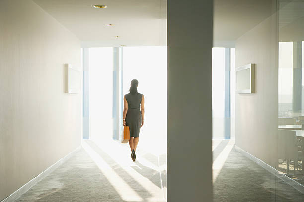 Why you’re not ‘behind’ — you’re just getting started. Photo of a woman walking through a corridor.