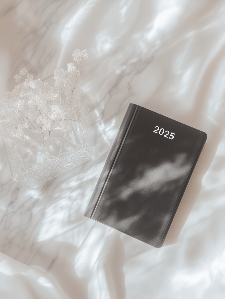 Time management: finding balance in the world of content creation. Marble background, 2025 black diary sat on marble.