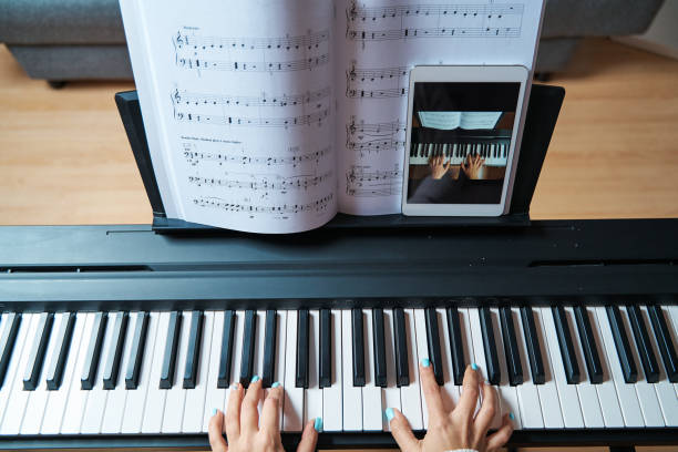 Songscription turns audio files into sheet music through AI. Photo of a keyboard with sheet music in front of it as well as a tablet.