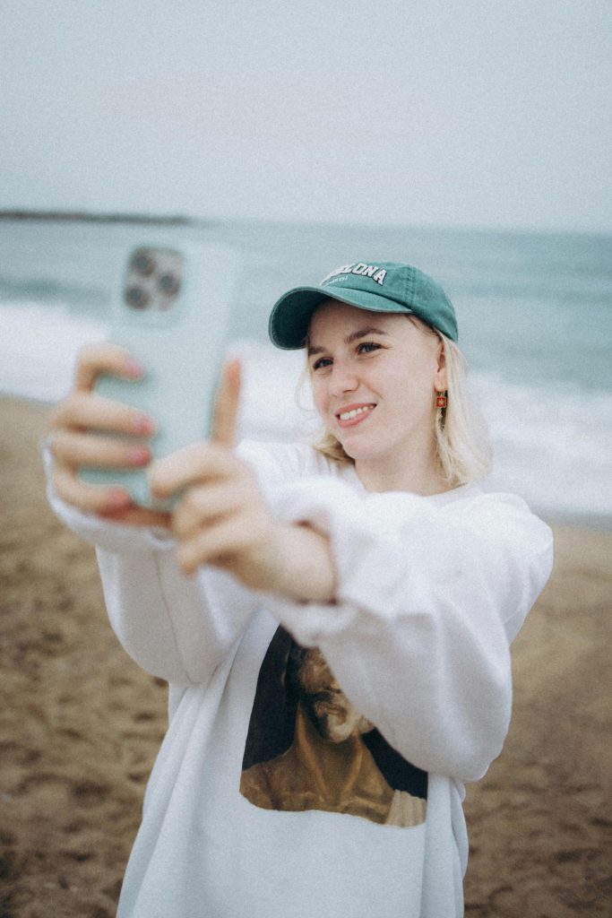 Beginner-friendly content ideas that don’t require showing your face. Photo of a girl recording herself on the beach via her smartphone.