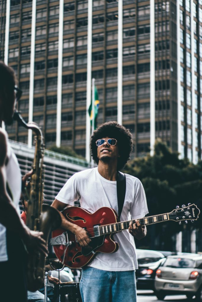 Understanding your rights as an independent musician. Photo of a man holding a guitar in a city.