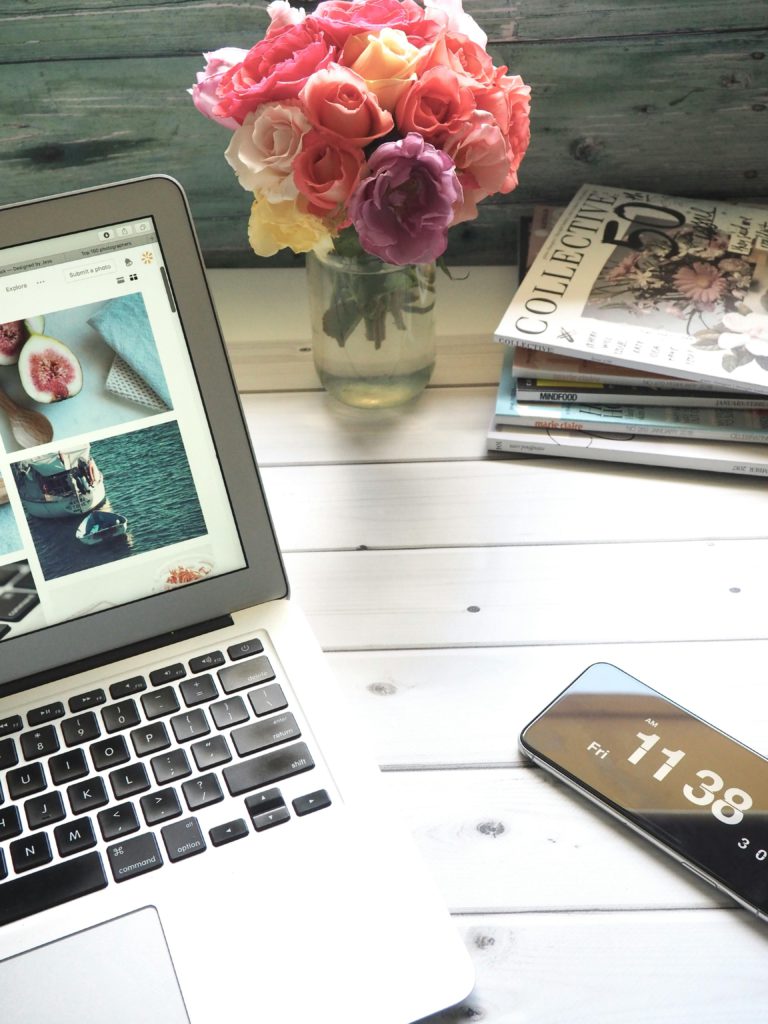 How to reach out to blogs, radios and influencers for music promotion. Photo of a laptop, flowers, magazines and a smartphone.