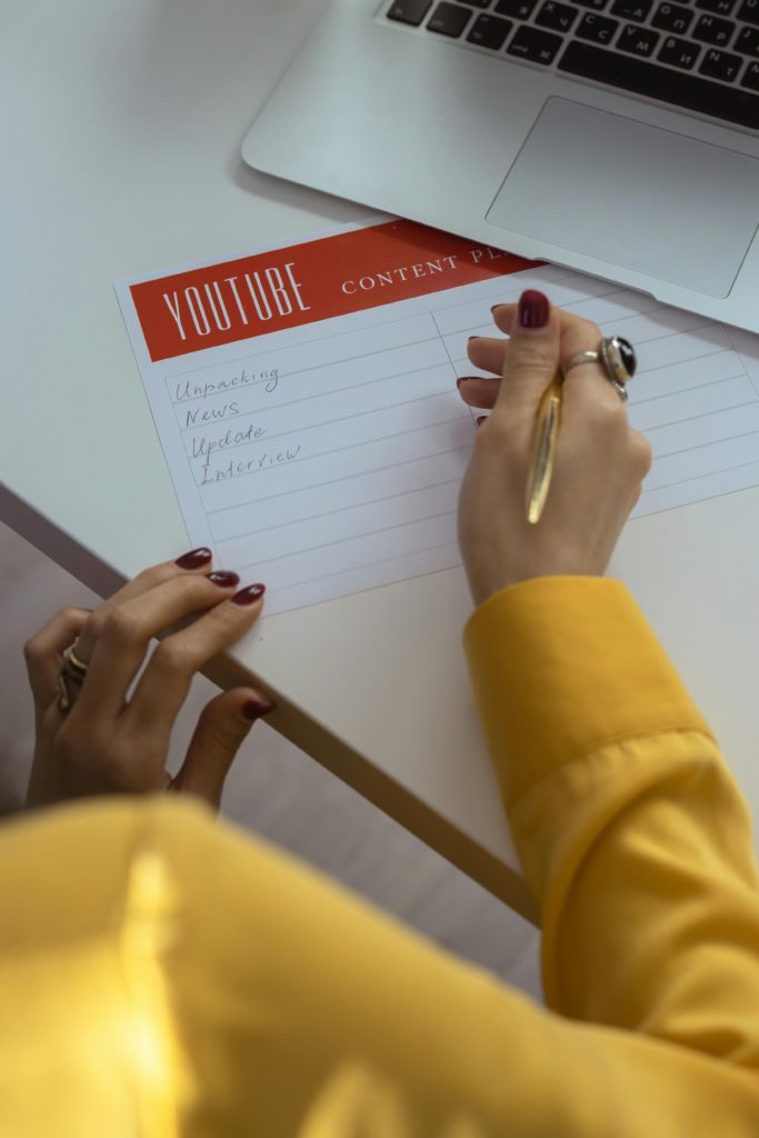 YouTube introduce their multi-language dubbing feature for. Photo of someone writing YouTube content ideas down.