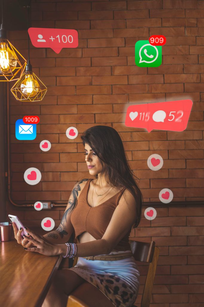 The difference between likes, comments, shares and saves. Photo of a woman on her phone, lots of likes emojis surrounding her.