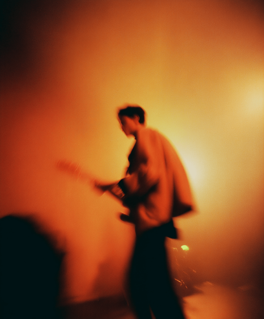 Building a long-term career in music, one release at a time.  Blurred photo of a man on a guitar.